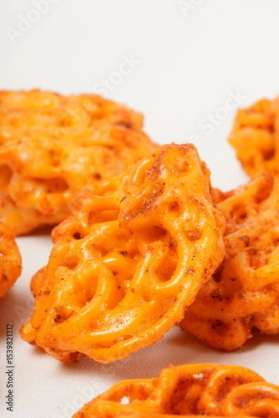 Fototapeta A pile of spicy Indonesian crackers or Kerupuk with spiral twists, coated in red-orange chili powder and rich spices. Bold, flavorful, and appetite-boosting. Photographed against a white background.