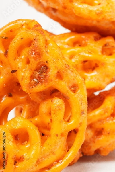 Fototapeta A pile of spicy Indonesian crackers or Kerupuk with spiral twists, coated in red-orange chili powder and rich spices. Bold, flavorful, and appetite-boosting. Photographed against a white background.