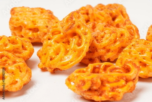 Fototapeta A pile of spicy Indonesian crackers or Kerupuk with spiral twists, coated in red-orange chili powder and rich spices. Bold, flavorful, and appetite-boosting. Photographed against a white background.
