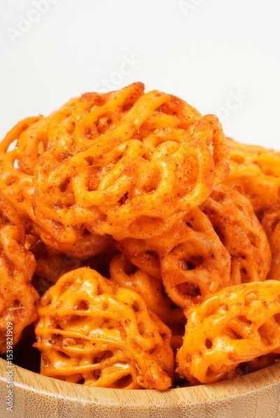 Fototapeta A pile of spicy Indonesian crackers or Kerupuk with spiral twists, coated in red-orange chili powder and rich spices. Bold, flavorful, and appetite-boosting. Photographed against a white background.