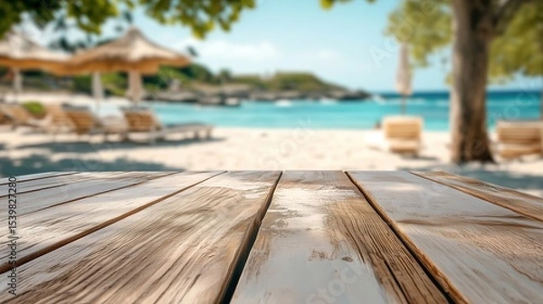 Fototapeta Empty wood table against  blurred shaded sun loungers on tropical beach. An ideal paradise background for summer product displays, vacation mockups, travel promotions.