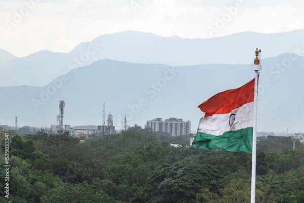 Fototapeta A large Indian national flag flies proudly in Madurai, set against a stunning backdrop of distant mountains