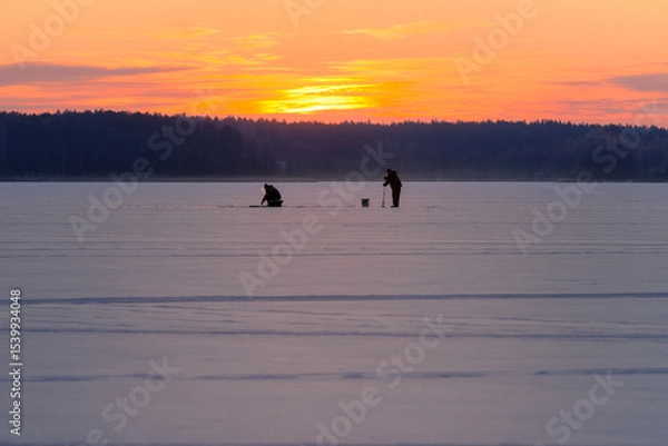 Fototapeta Silhouettes of People Making Ice Holes on Frozen Lake at Dawn — Winter Scene with Copy Space 