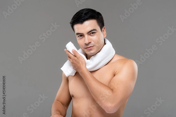 Fototapeta Shirtless man drying face with white towel after workout on gray background, men skin care and beauty concept