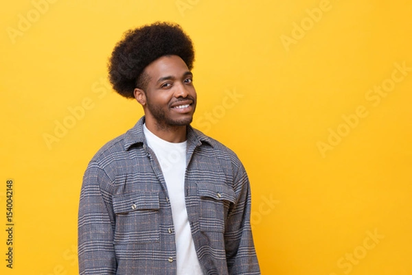 Fototapeta Happy man smiling confidently in casual outfit against yellow background
