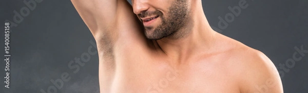 Fototapeta Closeup of young man spraying deodorant for body freshness and hygiene in gray studio banner background