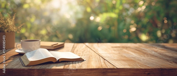 Obraz serene scene with open bible laying on the table outside, next to a coffee cup and tranquil green garden on sunny day scene; concept of bible study, calmness, searching for answers; copy space