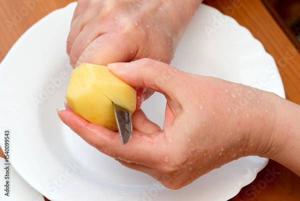 Obraz Peeling a potato with care in a cozy kitchen setting