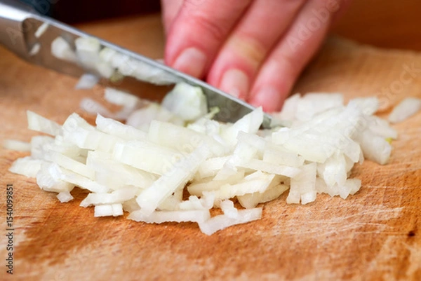 Obraz Chopping onions with precision on a wooden cutting board
