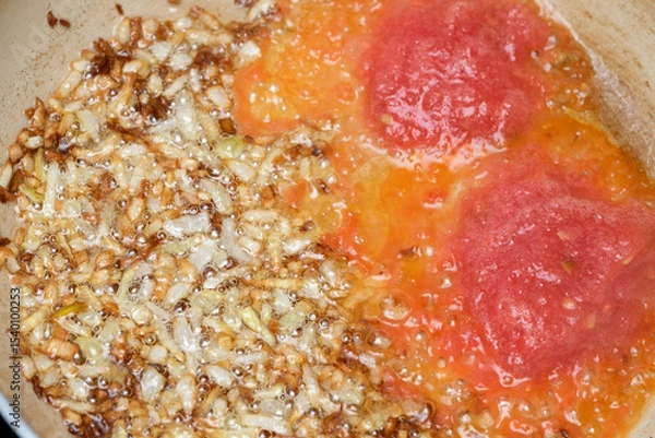Obraz Chopped onions fry in hot oil beside vibrant, fresh tomatoes in a pan