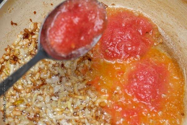 Obraz Cooking vibrant tomato sauce with caramelized onions on a rustic stove