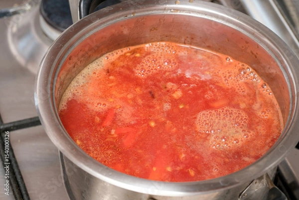 Obraz Cooking a vibrant tomato soup in a stainless steel pot on the stove