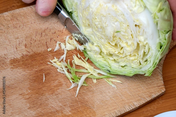 Obraz Chopping fresh cabbage on a wooden board for healthy meal preparation