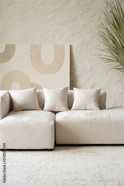 Obraz A spacious living area showcases a contemporary sectional sofa adorned with cushions, complemented by a large dried palm plant in a bright and airy setting.