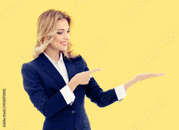 Fototapeta Portrait image - happy smile businesswoman show point hold some product, advertise. Business woman executive employee bank manager, teacher isolate orange yellow background with ad free space