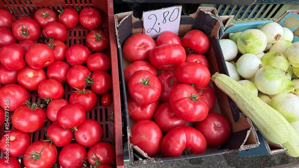 Obraz Assorted heirloom and traditional tomatoes and fresh onions displayed in crates at a local farmers market