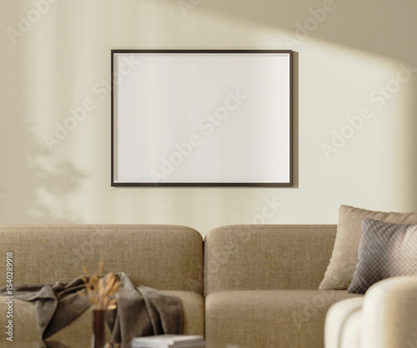Fototapeta blank picture frame mock up on a wall with sunlightith sunlight above brown sofa with pillows and decor, 3d render