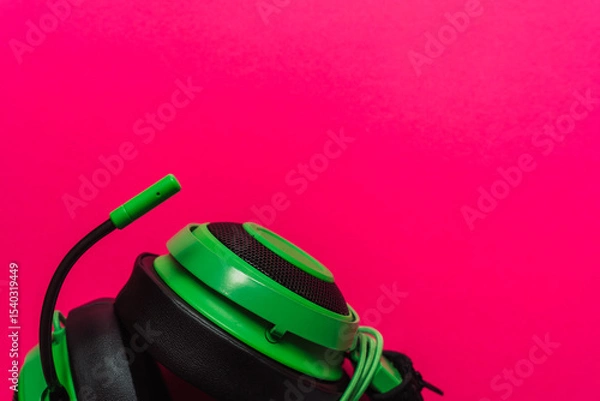 Fototapeta Bright green gaming headset with microphone on vibrant pink background. Bold composition in pop-art style, ideal for Gen Z themes and tech visuals. High quality photo