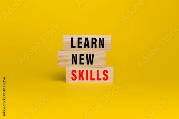 Fototapeta learn new skills words text on wooden blocks isolated on yellow background