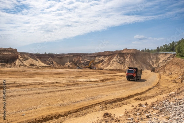 Fototapeta Active work in a sand quarry. Bucket trucks load sand into trucks.
