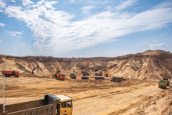 Fototapeta Active work in a sand quarry. Bucket trucks load sand into trucks.