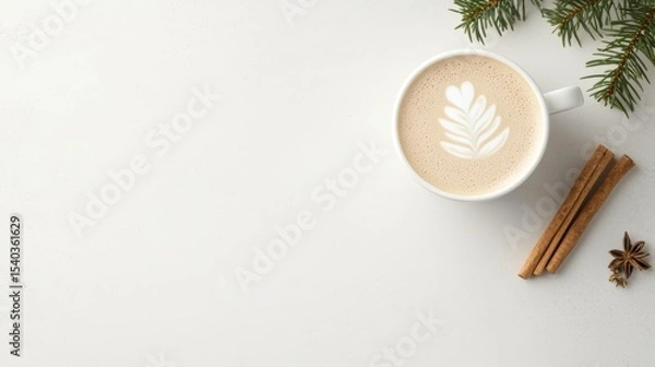 Fototapeta Flat lay of a festive latte with leaf latte art, cinnamon sticks, star anise, and pine branches on a white background. A cozy and minimal winter coffee scene perfect for seasonal designs.