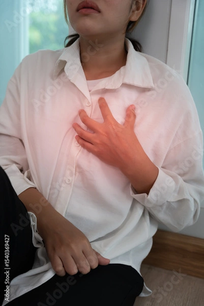 Fototapeta hand hold chest with heart attack symptoms, asian woman have chest pain caused by heart disease, leak, dilatation, enlarged coronary heart, press on the chest with a painful expressio