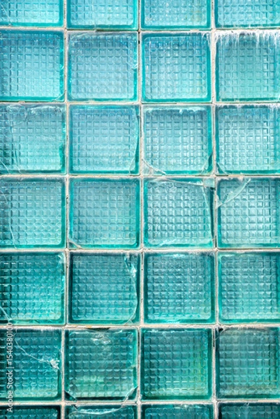 Fototapeta Transparent turquoise glass bricks with weathered surface texture showing interconnected cracks forming a chaotic pattern, vertical