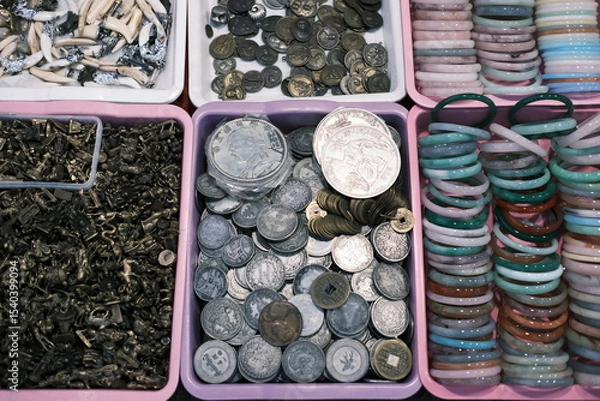 Fototapeta A collection of coins and bracelets are displayed in a pink container