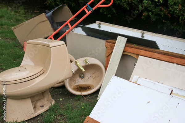 Obraz Discarded Bathroom Fixtures and Debris Piled on Grass during renovation