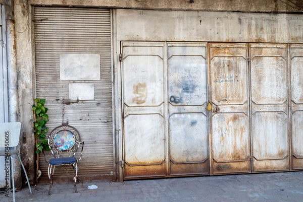 Fototapeta A Worn Urban Building With Multiple Shutted Storefronts And A Parked Car.