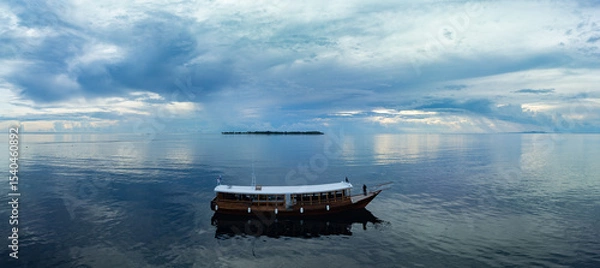 Obraz A dive boat drifts along the edge of a reef within Wakatobi National Park, off the coast of Sulawesi. This area is a popular destination for divers and snorkelers due to its high marine biodiversity.