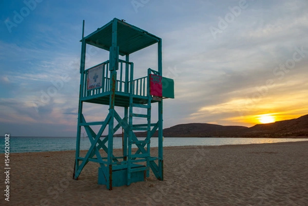 Fototapeta turquoise blue lifeguard high chair on the beach Simos on the island of Elafonisos with sunset in peloponnese , Greece