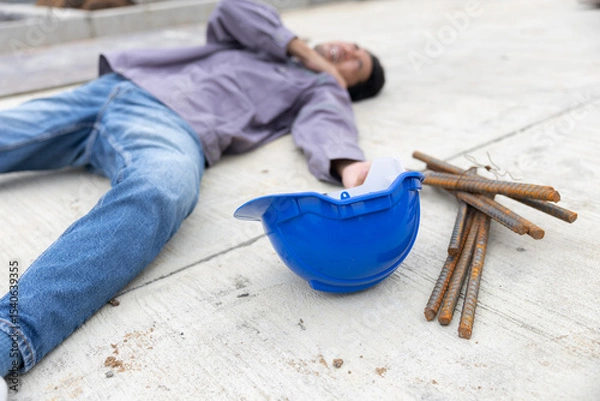 Fototapeta Worker lies on construction site floor with safety helmet suffer from accident