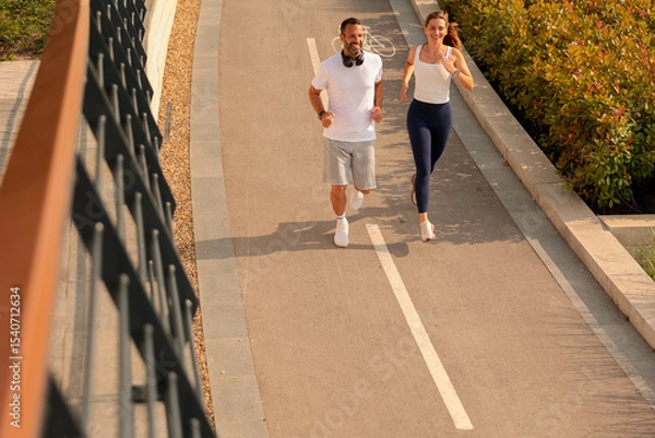 Obraz Running together along a peaceful path surrounded by greenery in the bright morning sun