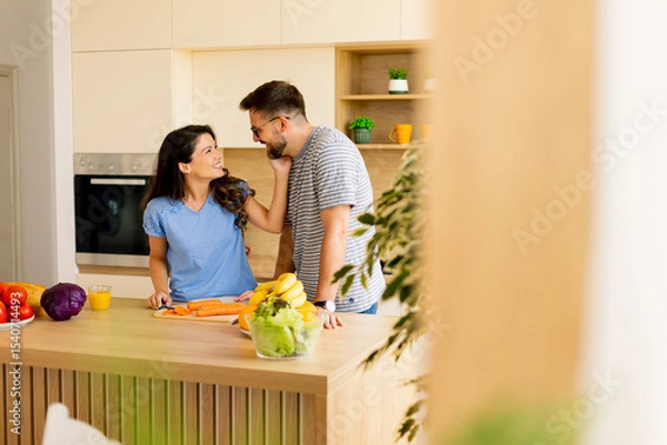 Obraz Couple enjoying quality time together while preparing a healthy meal in a bright modern kitchen