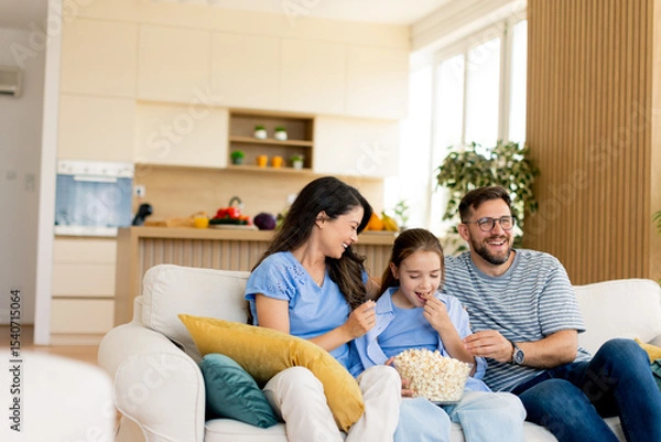 Obraz Family enjoying a cozy movie night at home with popcorn and laughter in a bright living room setting