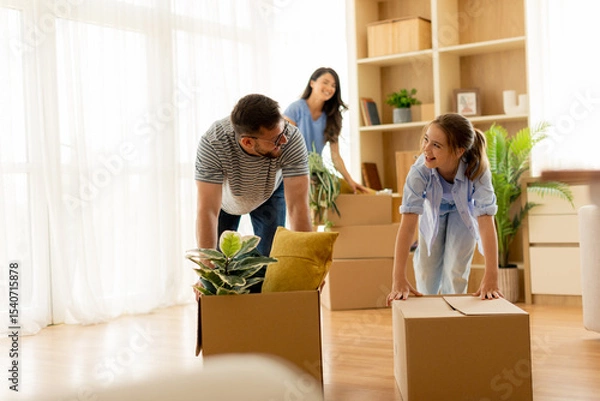 Obraz Family enjoys unpacking boxes while moving into their new home, filled with laughter and joy in the bright living room