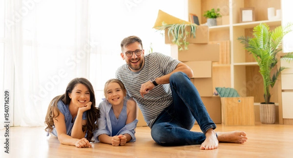 Obraz Family enjoys a sunny afternoon together in their new living room filled with boxes and greenery