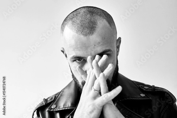 Fototapeta A black and white portrait of a man with hands clasped, looking directly at the camera.