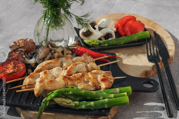 Fototapeta Barbecue on bamboo sticks. Grilled chicken kebab with mushrooms, asparagus and tomato. Red hot kebab.