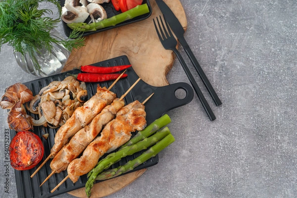 Fototapeta Barbecue on bamboo sticks. Grilled chicken kebab with mushrooms, asparagus and tomato. Red hot kebab. Top view, copy space