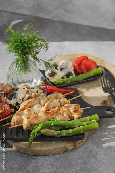 Fototapeta Barbecue on bamboo sticks. Grilled chicken kebab with mushrooms, asparagus and tomato. Red hot kebab.