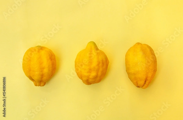 Obraz Three fresh lemons on yellow background. Flat lay, top view