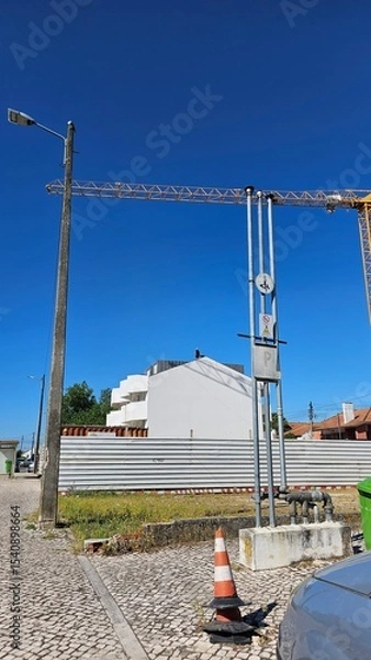 Fototapeta Urban Construction Scene with White Building, Cranes and Traffic Cone