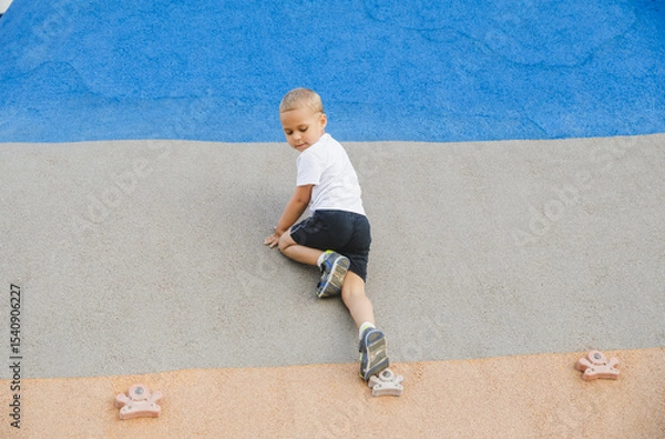 Obraz little boy climbing stone wall on playground. sport life concept
