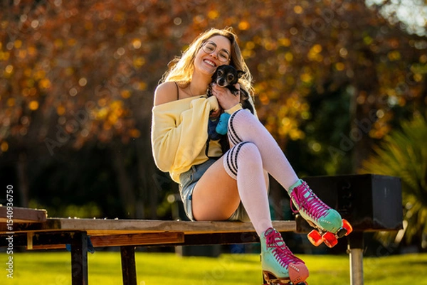 Fototapeta A Cheerful Skater Joyfully Holds a Small Dog in Her Arms as She Enjoys a Beautiful, Sunny Day Surrounded by the Lively Atmosphere of a Vibrant Park