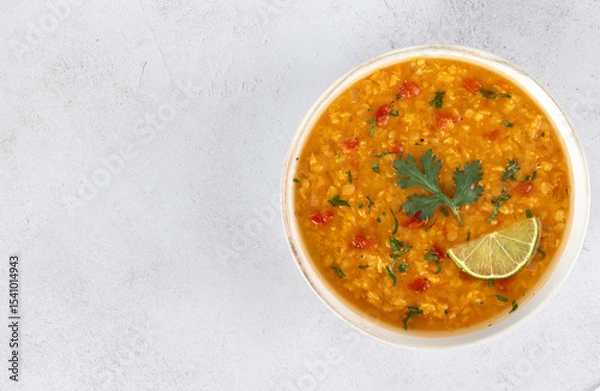 Fototapeta Traditional Indian dal soup with red lentils, spices, fresh cilantro and lime on a white background. Indian food