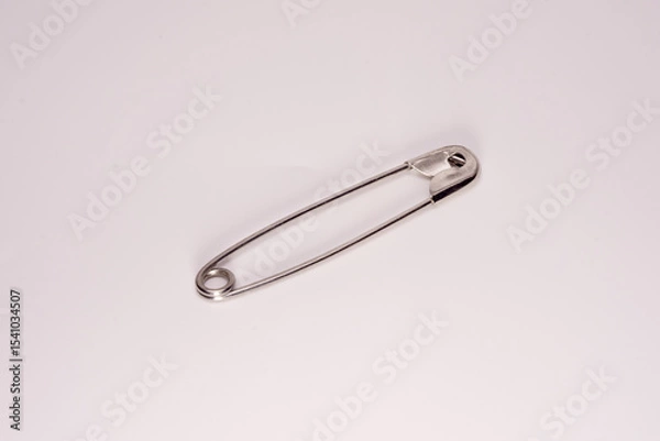 Obraz A close-up of a silver safety pin in the closed position, isolated on a white background. Ideal for concepts of sewing, safety, minimalism, or everyday objects