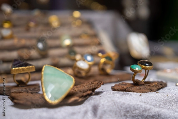 Fototapeta A collection of elegant gemstone rings artfully displayed on rustic wood. each ring features unique stones, creating a captivating scene perfect for jewelry enthusiasts and designers.